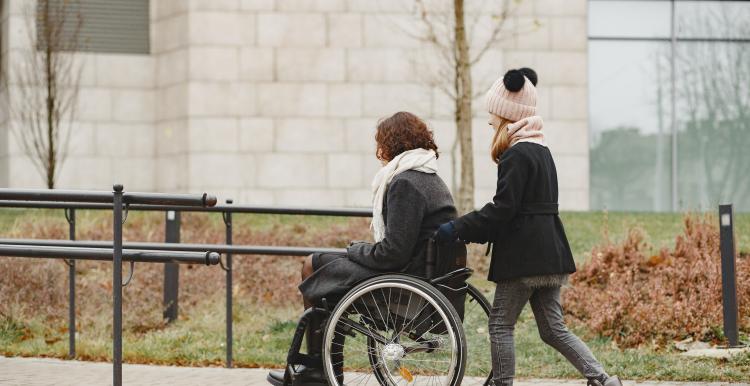 Female in wheelchair being pushed by carer outside