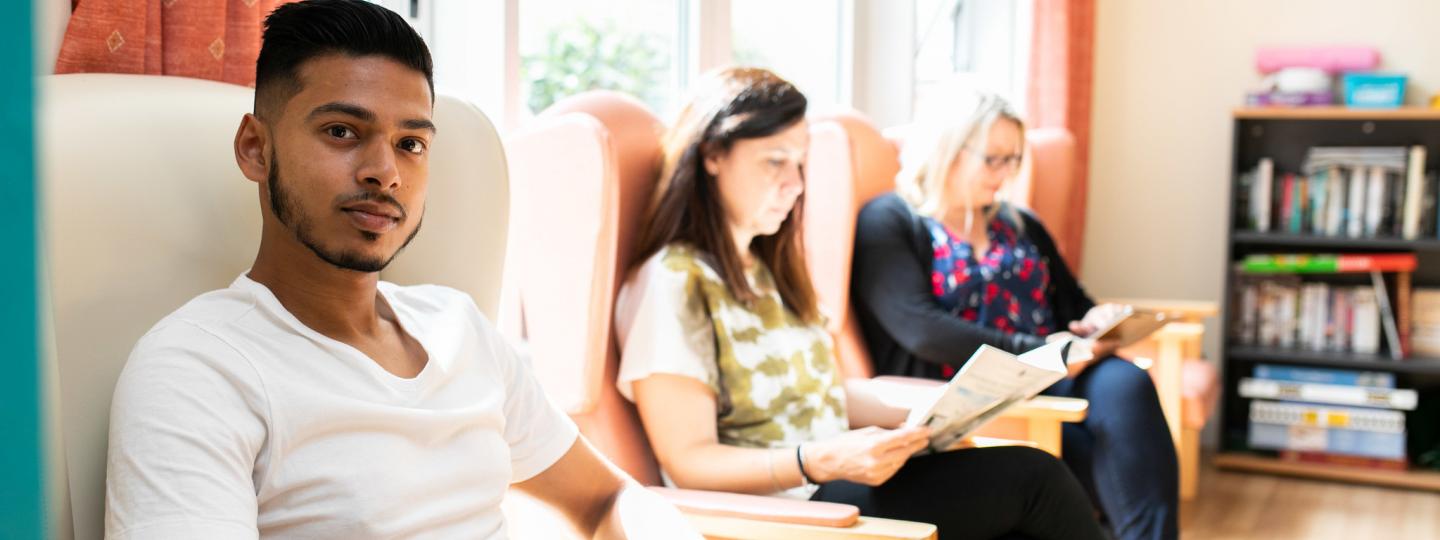 Three people sitting in some chairs in a waiting area